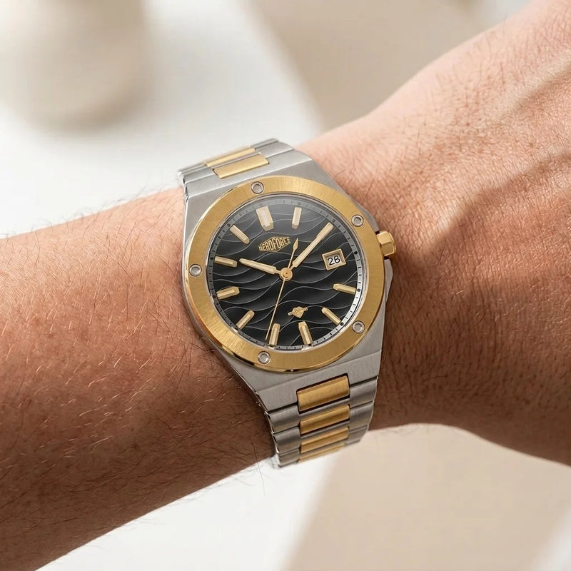 Two tone stainless steel wristwatch with a black wave patterned dial worn on a person's wrist.