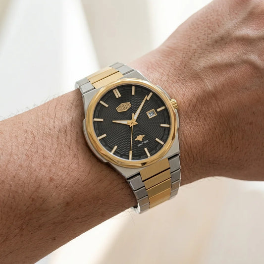 A two-tone stainless steel and gold wristwatch with a black textured dial, shown worn on a person's wrist.